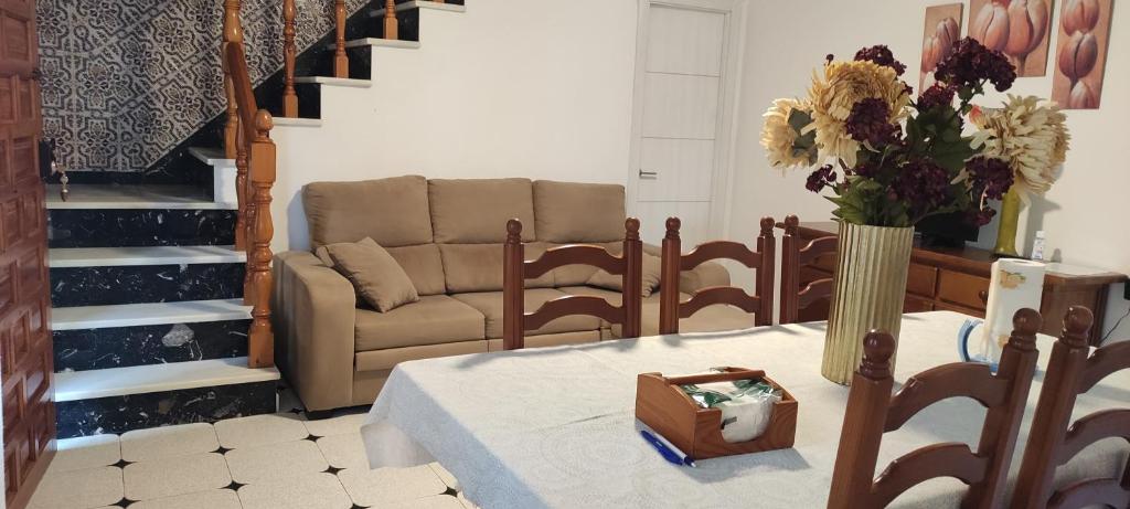 a living room with a couch and a table with flowers at Casa en el centro del pueblo in Conil de la Frontera