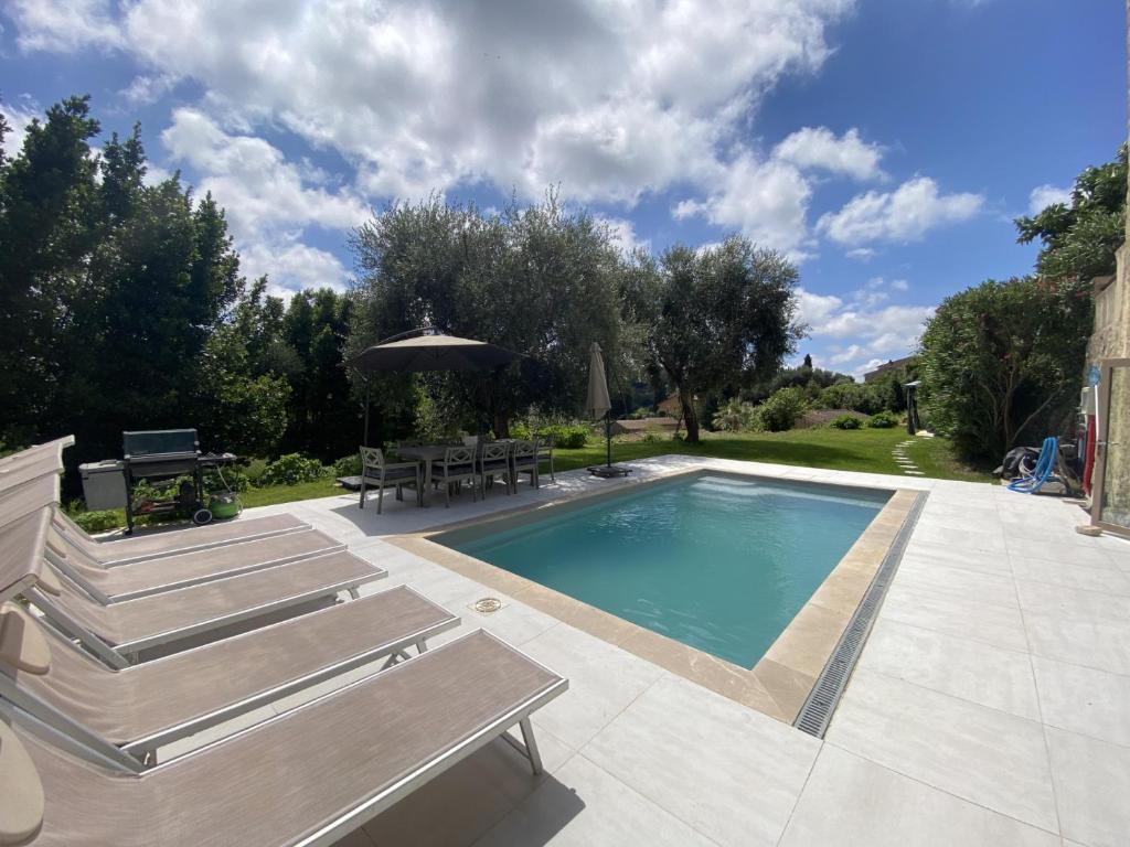 a swimming pool with benches and a table and an umbrella at Bastide de Peyloubet in Grasse