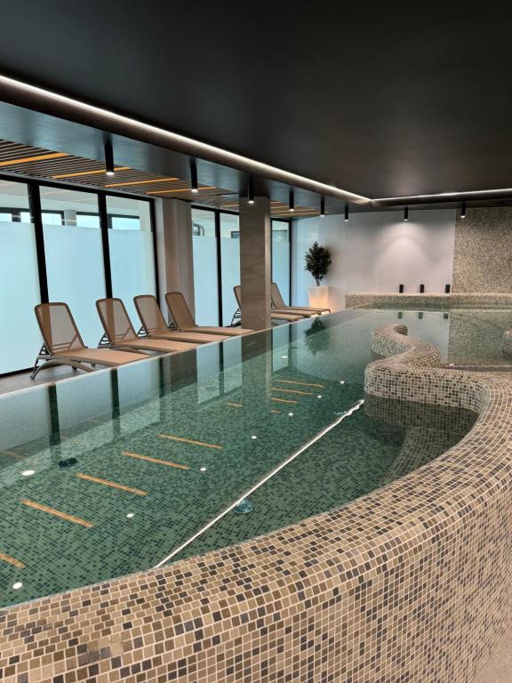 a pool in a hotel with chairs and a table at Baltic Waves Resort Luksusowy apartamnet z basenem i parkingiem in Międzyzdroje