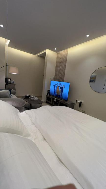 una camera da letto con un grande letto bianco e una TV a schermo piatto di استديو بموقع مميز بدخـول ذاتي a Riyad
