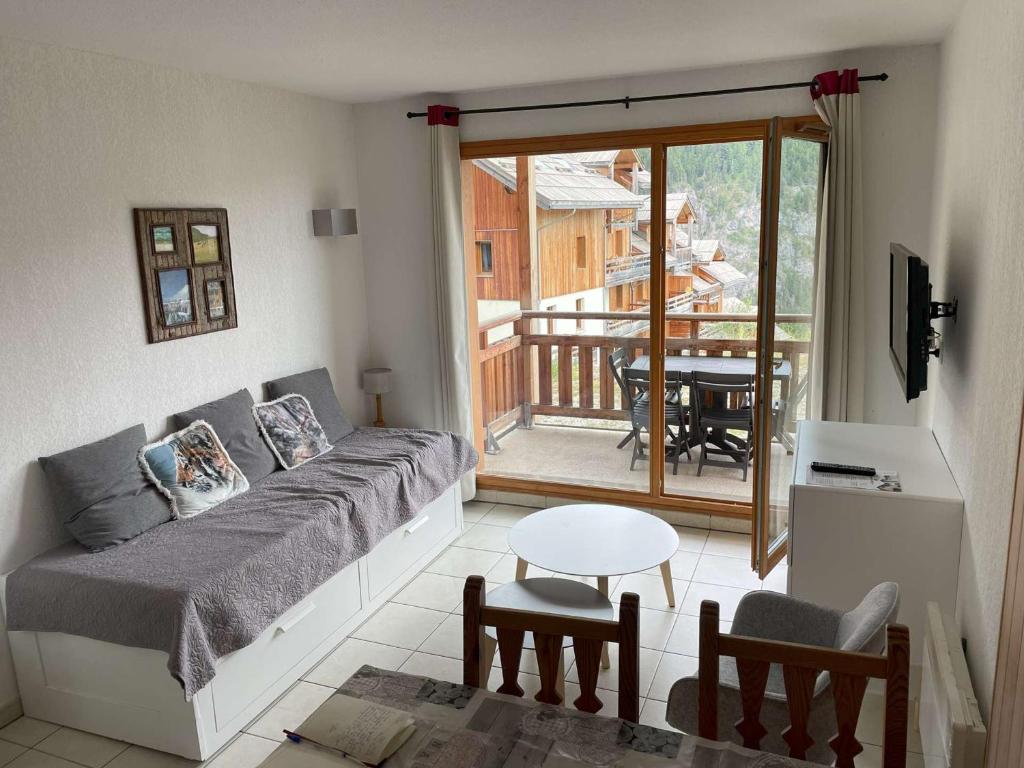- un salon avec un lit et un balcon dans l'établissement Appartement Les Orres 6 pers avec piscine et animaux admis - FR-1-322-452, aux Orres
