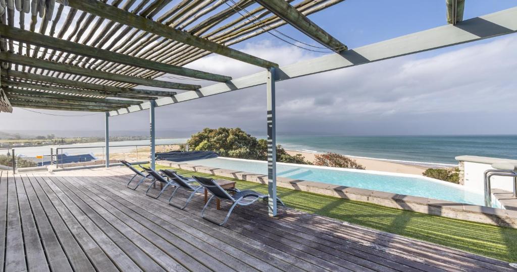 a deck with chairs and a pool and the ocean at Hideaways Mariners Moon, Plettenberg Bay in Plettenberg Bay
