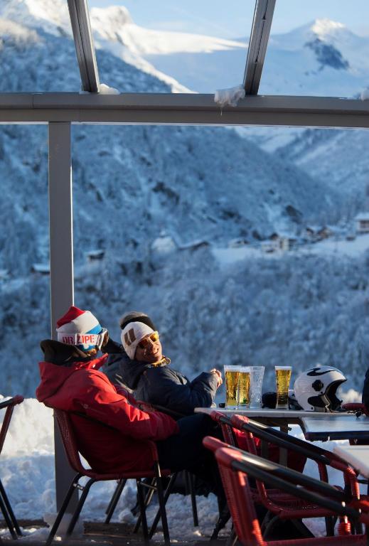 two people sitting at a table with a view of a mountain at Catrina Lodge in Disentis