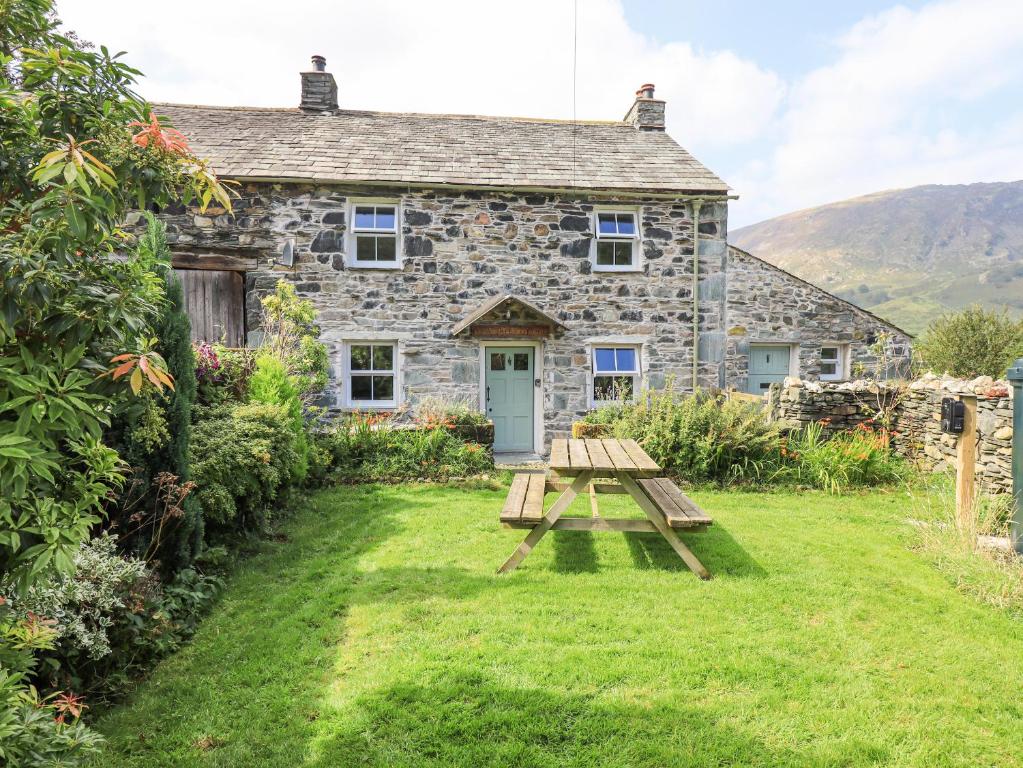 a stone house with a picnic table in front of it at Yew Tree Cottage Borrowdale in Rosthwaite