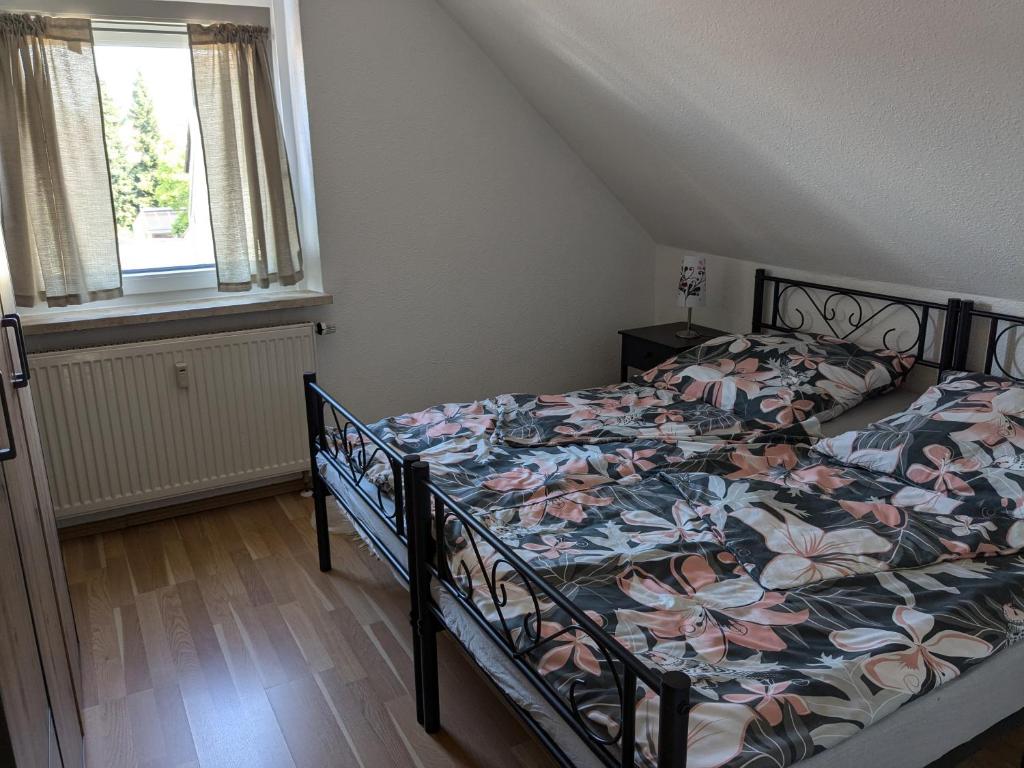 1 Schlafzimmer mit einem Bett mit einer Blumendecke und einem Fenster in der Unterkunft Ferienwohnung Alafia in Veitsbronn