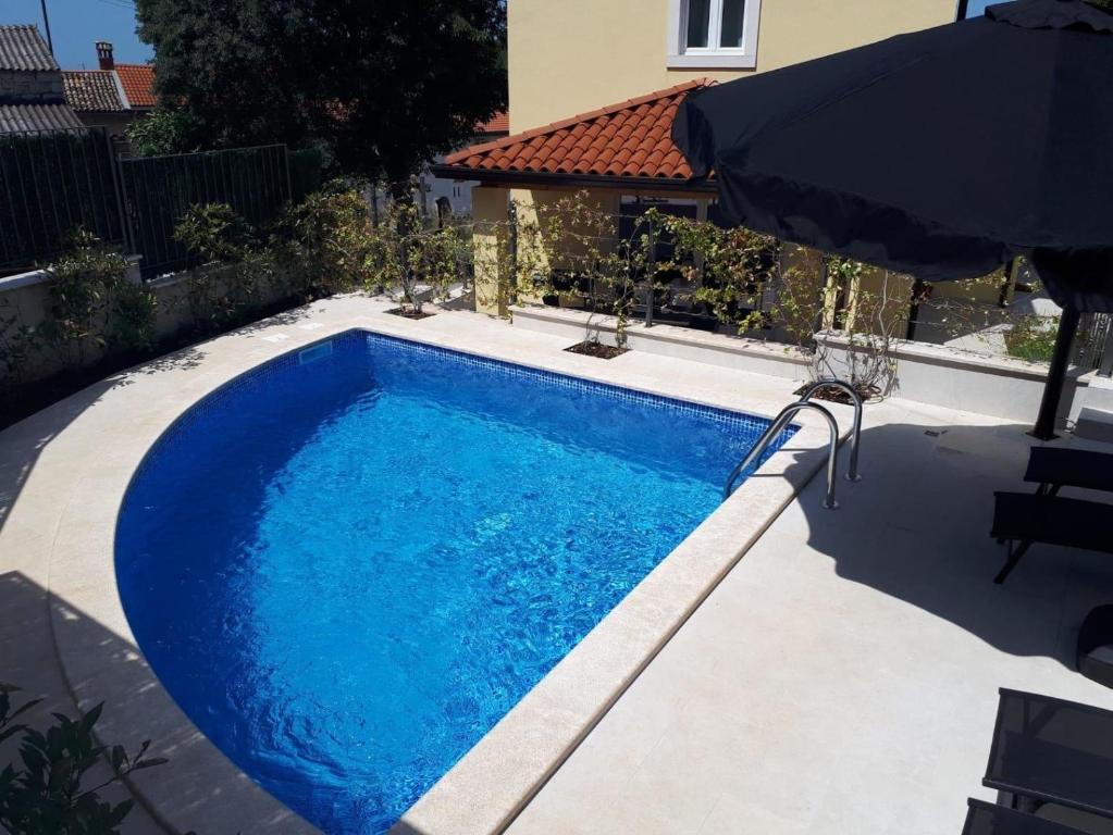 a swimming pool in a yard with an umbrella at Ferienhaus mit Privatpool für 8 Personen ca 120 qm in Mugeba, Istrien Istrische Riviera in Mugeba