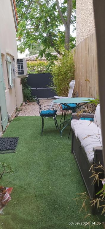 a patio with a table and chairs on the grass at la maison de josy in Aix-en-Provence