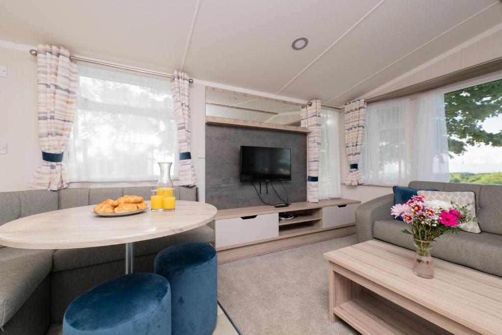 a living room with a table and a couch and a tv at Tencreek Holiday Park in Looe
