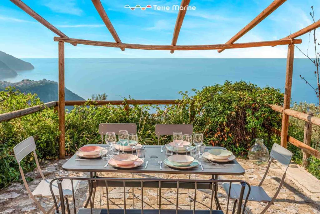 a table with wine glasses and a view of the ocean at Blu Isola, Terre Marine in Corniglia