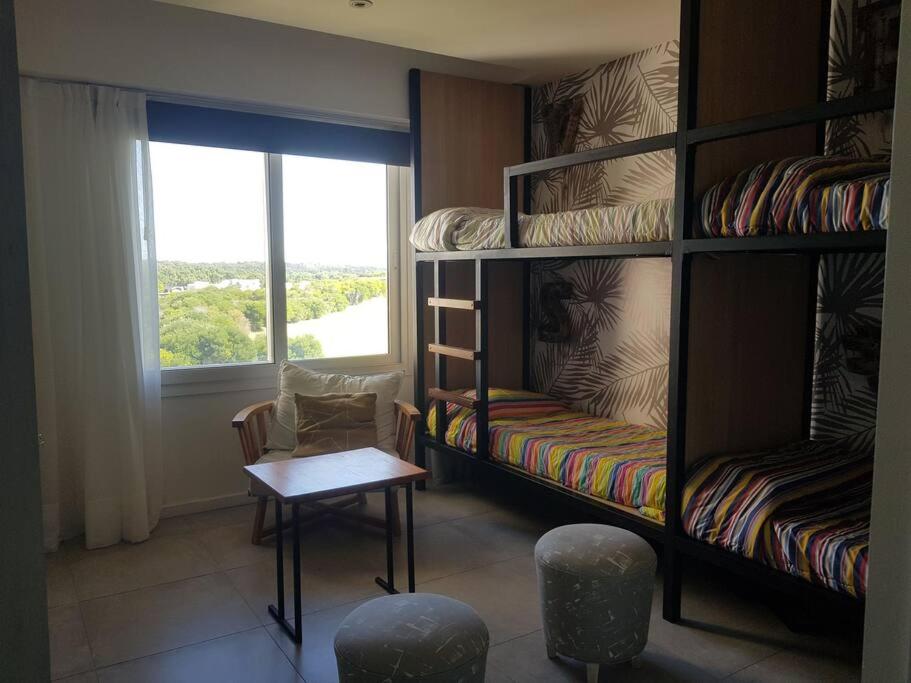 a room with bunk beds and a table and a window at Departamento con vista al Golf Barrio Costa Esmeralda in Costa Esmeralda