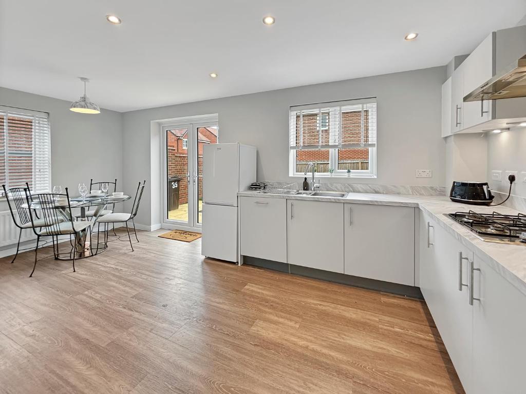 a kitchen with white cabinets and a table with chairs at Amaya Seven - Luxury 3 bedroom detached house with garden & driveway - Sleeps 7 - Bottesford, Leicestershire in Bottesford