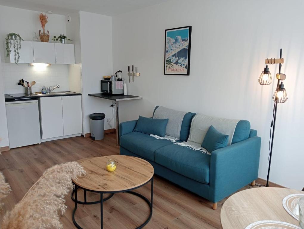 un salon avec un canapé bleu et une table dans l'établissement L'escale bleue Méditerranée, à La Grande Motte