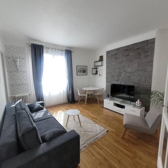 ein Wohnzimmer mit Sofa und Fernseher in der Unterkunft Appartement cosy proche Paris in Colombes