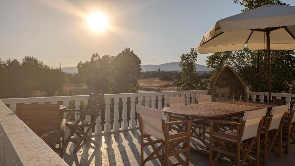 a wooden table and chairs on a balcony with an umbrella at Feraklion House in Haraki