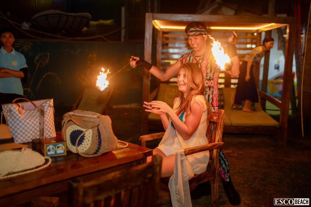 a woman sitting in a chair with a man holding torches at Athenia Hoi An Boutique Hotel & Spa in Hoi An