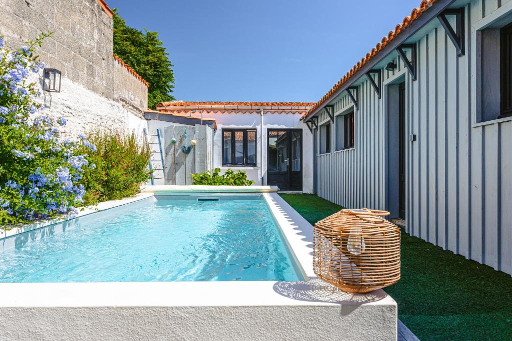 a swimming pool with a wicker basket next to a house at Maison 4 chambres avec piscine in Le Château-dʼOléron