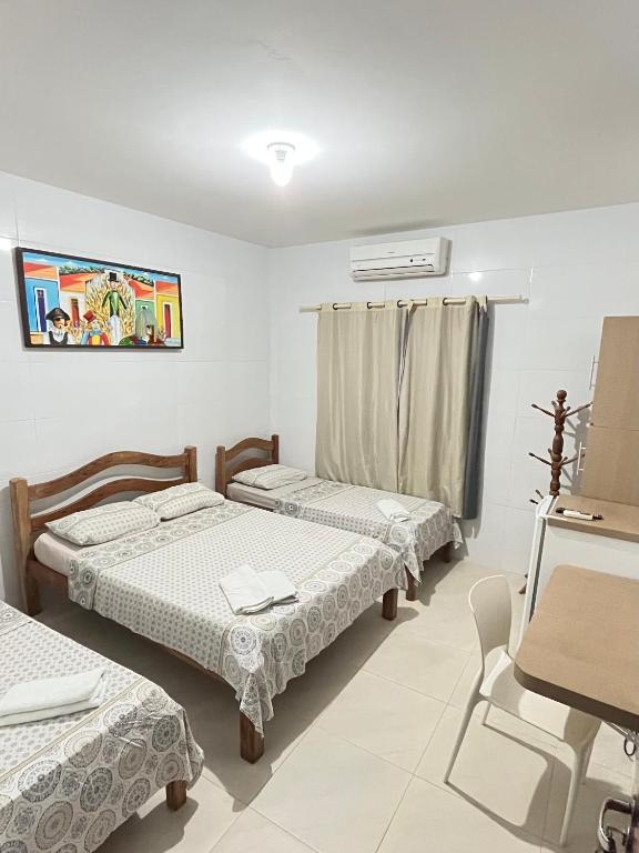 a room with three beds and a table and chairs at Paraíso Olindense in Olinda