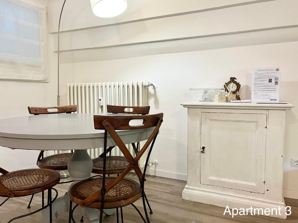 tavolo e sedie in una stanza con orologio appeso a un muro di MeModena Apartments a Modena