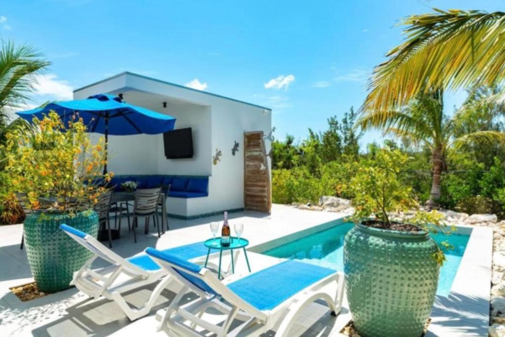 a villa with a swimming pool with chairs and a tv at Grace Bay Vacation Villa in Long Bay Hills