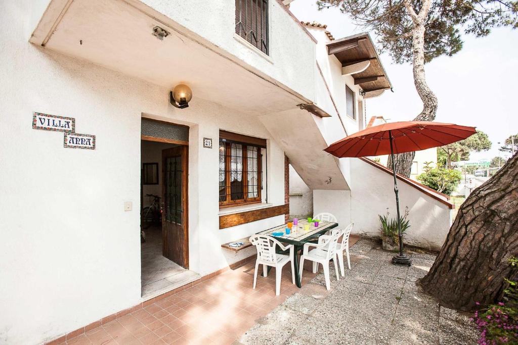 Un patio con una mesa y sillas y una sombrilla. en Quiet little villa by the seaside in Rosolina Mare, en Rosolina Mare