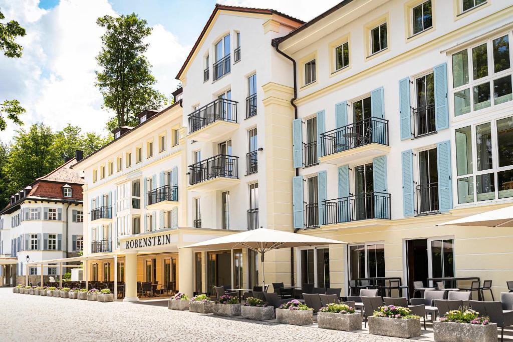Un gran edificio con mesas y sombrillas delante. en Robenstein Aktivhotel &amp; SPA, en Zwiesel