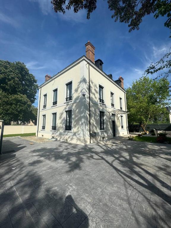 une grande maison blanche avec une grande allée dans l'établissement L'étoile de Seine 77 Appartement 6, à Dammarie-les-Lys