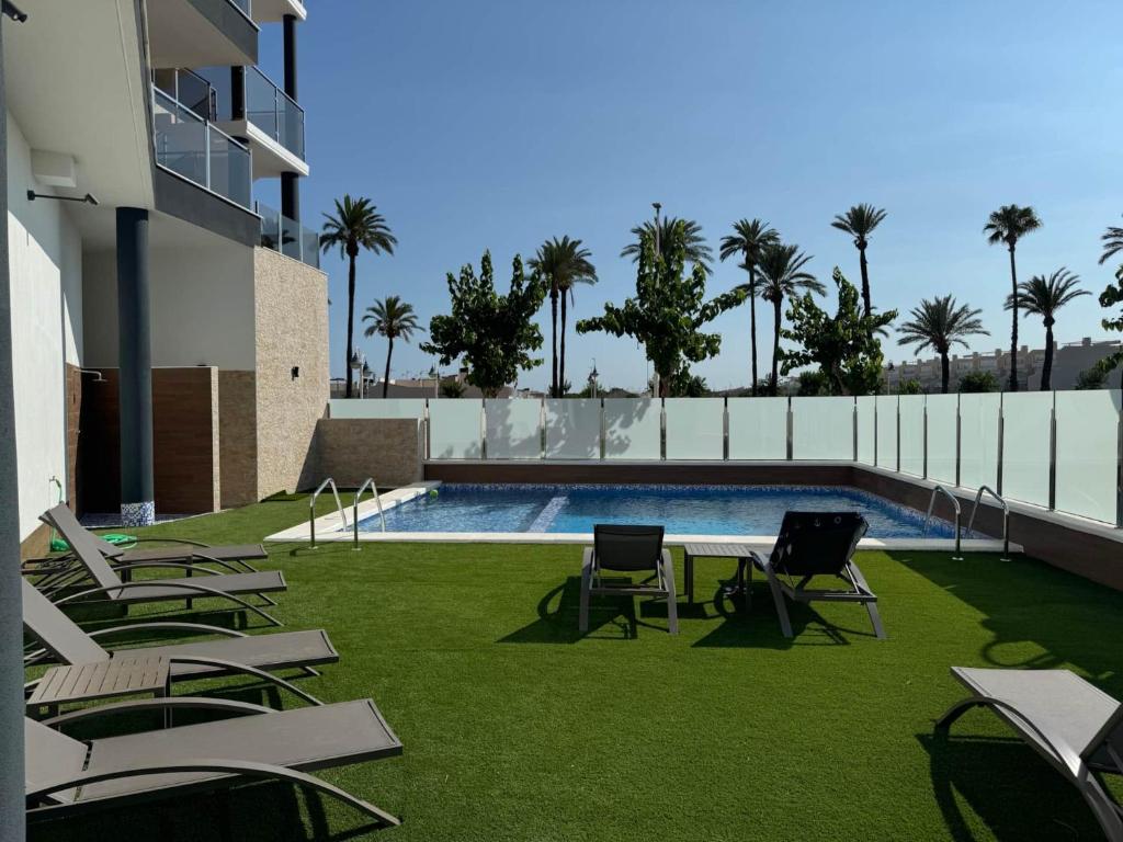 a group of chairs sitting on the grass near a swimming pool at Casa Virginia in Los Alcázares