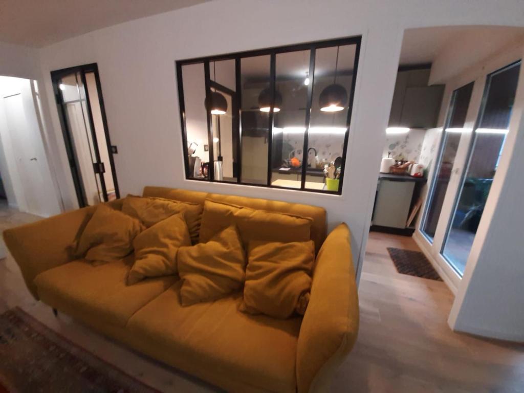 - un canapé brun dans le salon doté de fenêtres dans l'établissement VANNES au CALME proche centre et port, à Vannes