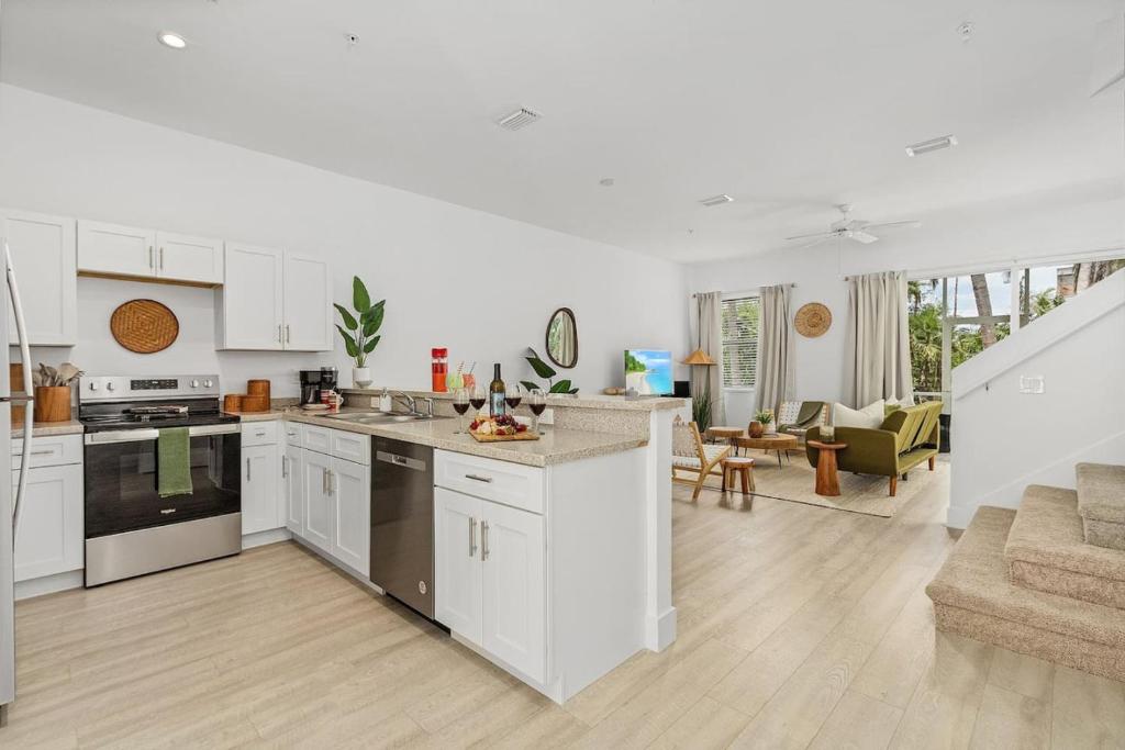 a kitchen with white cabinets and a living room at Paradise at Hidden Palms Cove in Fort Myers