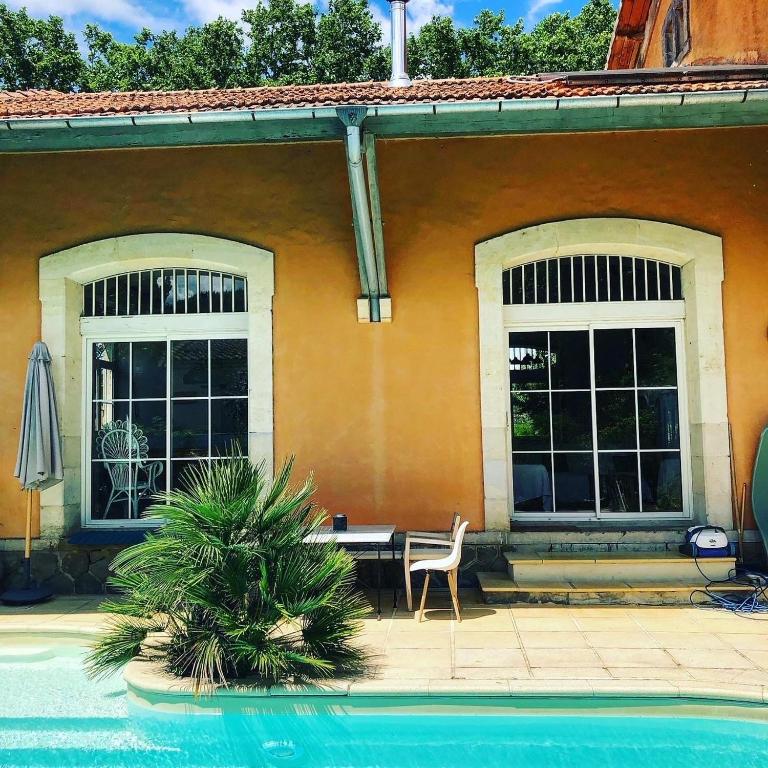 a house with a table and a chair next to a pool at Chic trainstation in Pomas
