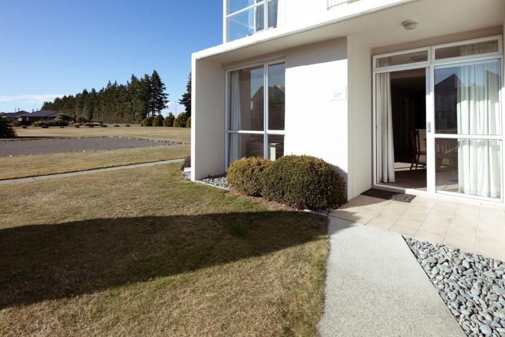 a white house with a walkway next to a yard at Central Methven 3-Bedroom Apartment in Methven