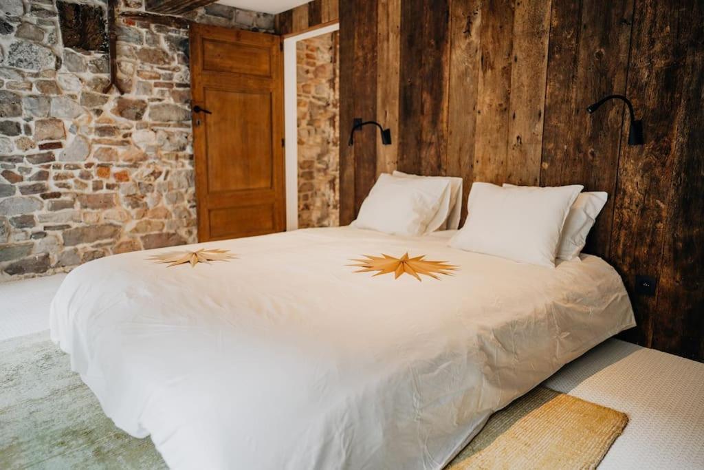 a bedroom with a large white bed with wooden walls at Appart'24 Cosy au centre de Huy in Huy