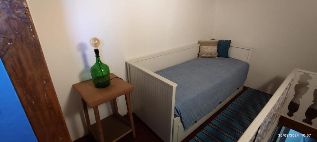 a small bedroom with a bed and a vase on a table at Casa do Outeirinho in Castelo de Vide