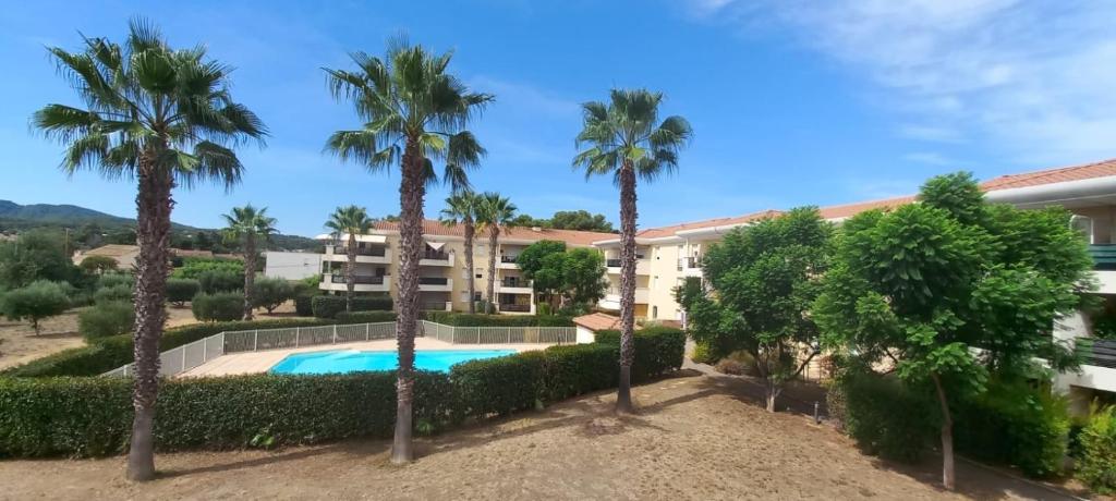 un complexe avec piscine et palmiers dans l'établissement L’azuréenne vue sur piscine, à La Seyne-sur-Mer