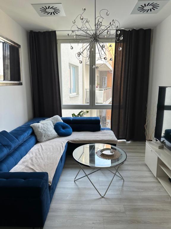 Una sala de estar con un sofá azul y una mesa de cristal. en Majestic Old Town Apartments, en Bratislava