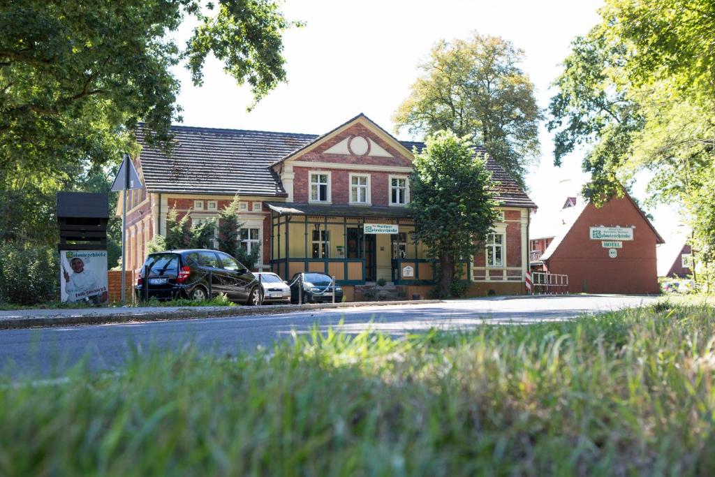 una grande casa con macchine parcheggiate di fronte di Hotel Kolonieschänke a Burg