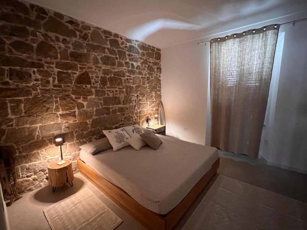 a bedroom with a bed and a stone wall at Regina di Cuori in La Maddalena