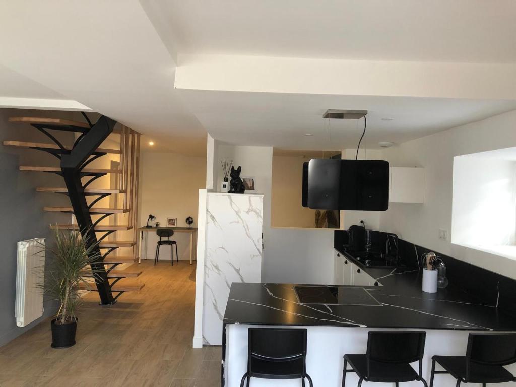 a kitchen with a black counter and black chairs at Charmante maison in Château-Gontier