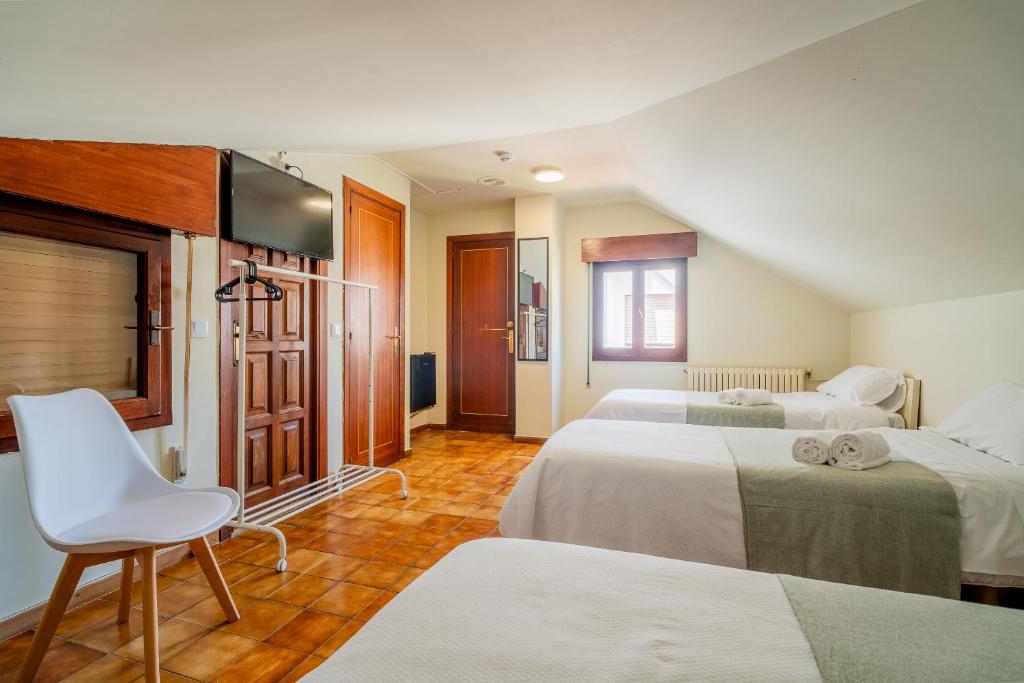 a hotel room with two beds and a chair at Alojamientos Valdecilla 3000 in Santander