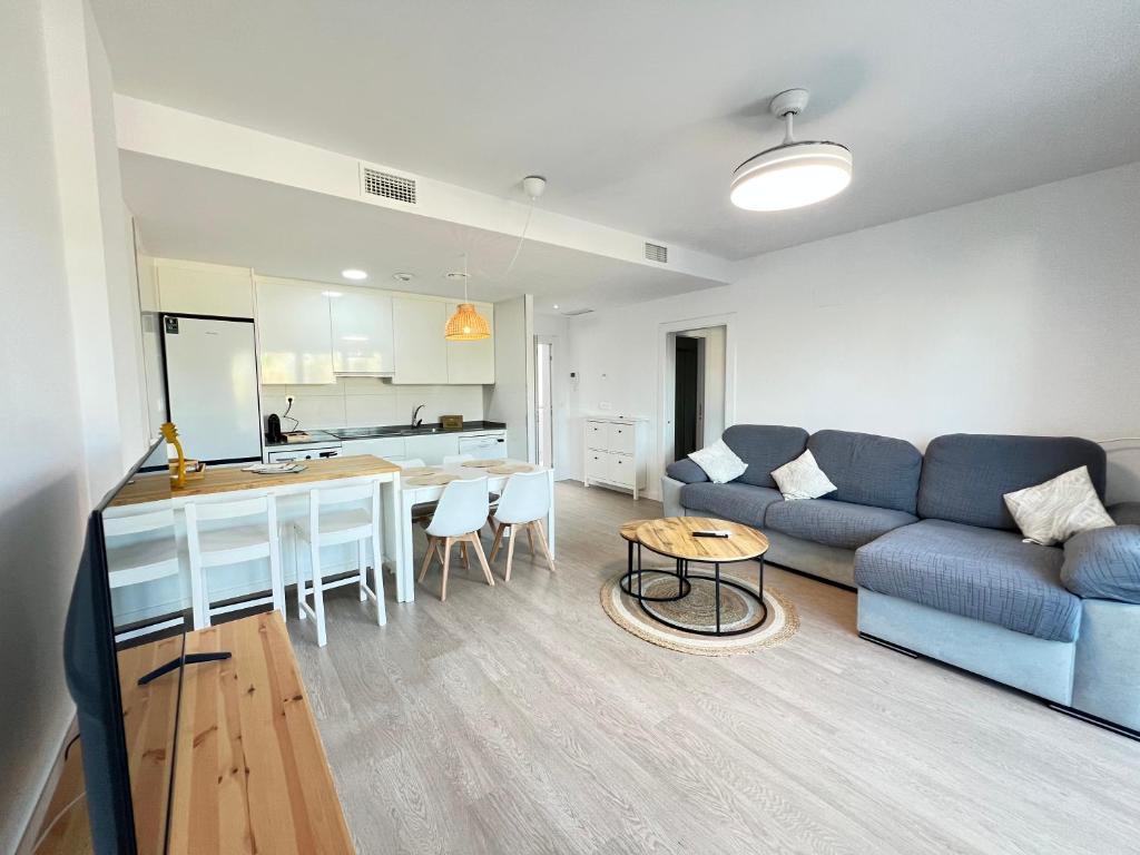Una sala de estar con un sofá azul y una cocina. en PUSHE Playa Granada Beach & Golf 8, en Motril