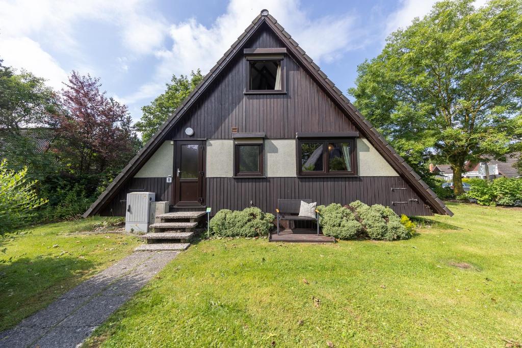 a black and white house with a grass yard at Ferienhaus Robbenplate 11 in Dorum-Neufeld