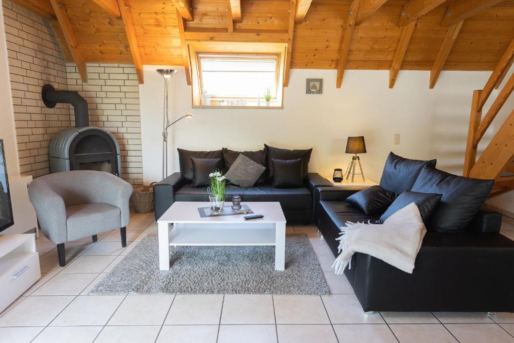 ein Wohnzimmer mit einer schwarzen Couch und einem Tisch in der Unterkunft Ferienhaus Westertill 03 in Dorum Neufeld