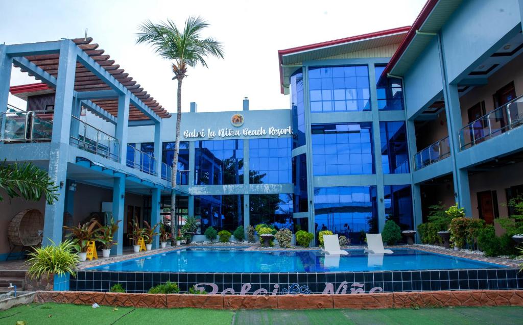 a building with a swimming pool in front of it at Balai La Niña Beach Resort in Aclan
