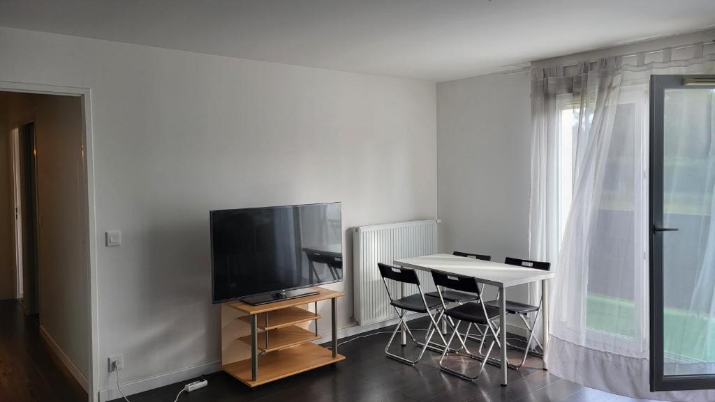 un salon avec une télévision, une table et des chaises dans l'établissement B&B Sweet Meauxtown - Gare de Meaux, à Villenoy