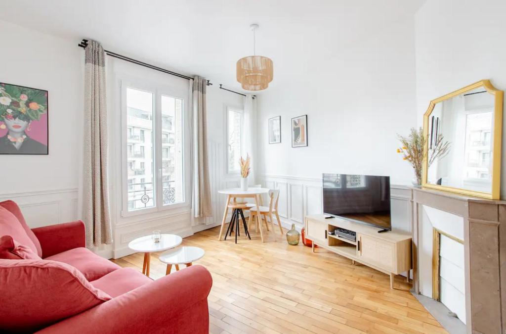 a living room with a red couch and a television at Charmant Appartement Cosy à Suresnes in Suresnes