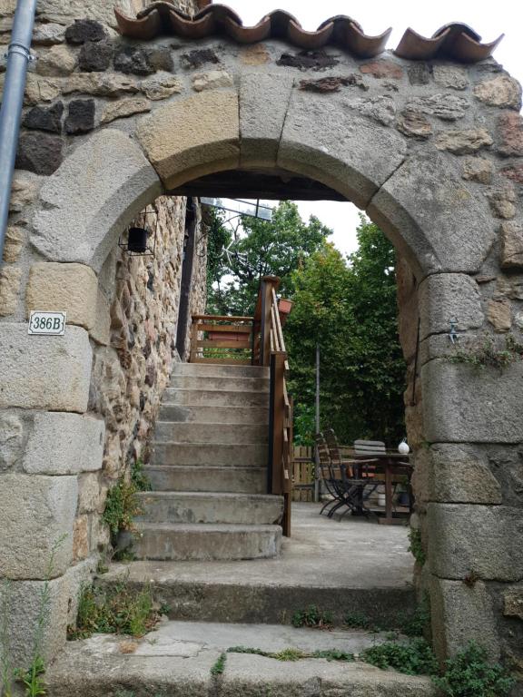 une arche menant à un bâtiment en pierre avec des escaliers dans l'établissement Maison en pierre de hameau, à Aizac