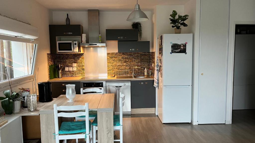 Il comprend une cuisine équipée d'un réfrigérateur blanc, d'une table et de chaises. dans l'établissement St Nazaire proche plage, à Saint-Nazaire