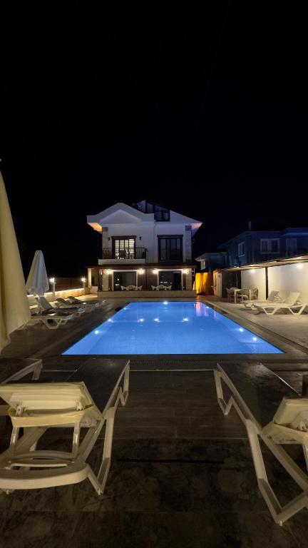 a swimming pool at night with chairs and a house at Villa Burçin Apart in Dalyan