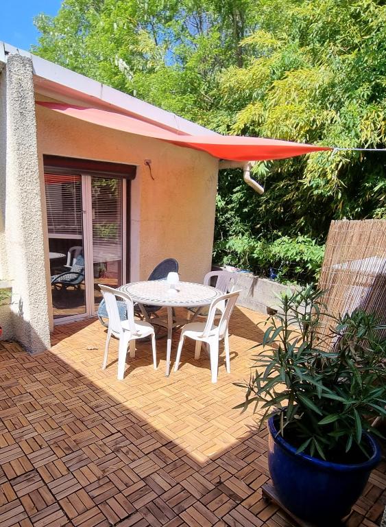 un patio avec une table et des chaises sur une terrasse dans l'établissement Casa Sereno - Appartement avec piscine chauffée et couverte, à Saint-Laurent-du-Pape