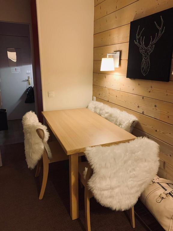 - une table à manger avec 2 chaises blanches et une table en bois dans l'établissement APPARTEMENT charme SPA & PARKING COUVERT Au pied des pistes Plagne 1800, à La Plagne Tarentaise